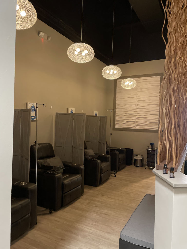 A quiet relaxation space with a row of leather recliners divided by panels for privacy. The room is accented by warm pendant lighting and a textured wall panel for a minimalist aesthetic.